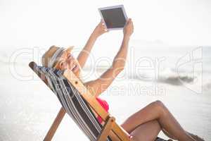 Happy woman talking a selfie on a digital tablet