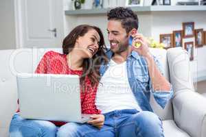 Cheerful couple using laptop while discussing