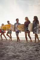 Happy friends walking with surfboards
