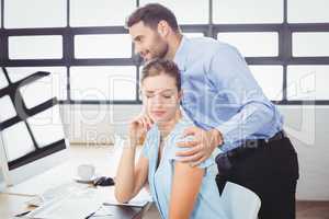 Businessman harassing female colleague at computer desk