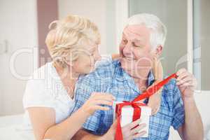 Happy senior couple opening gift