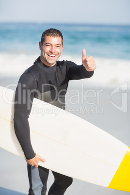 Portrait of happy man holding a surfboard on the beach