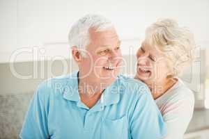 Senior woman embracing husband from behind in kitchen
