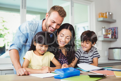 Happy parents assisting children doing homework