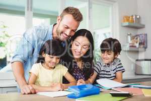 Happy parents assisting children doing homework