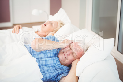 Disturbed man covering ears from snoring wife