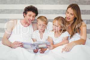 Family reading book on bed
