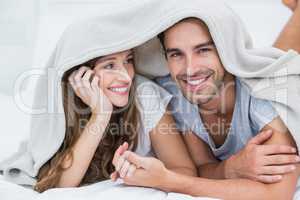 Happy couple enjoying under blanket