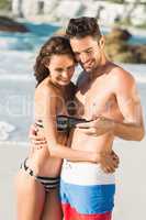 Couple embracing and looking at smartphone