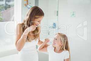 Smiling mother and daughter brushing teeth