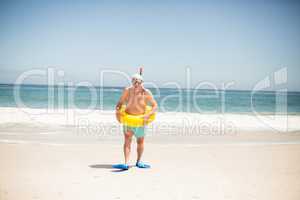 Senior man with swimming ring and flippers at the beach