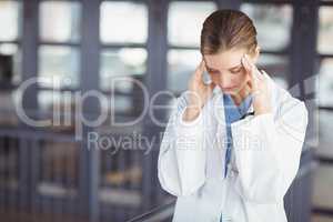 Tensed female doctor with head in hands