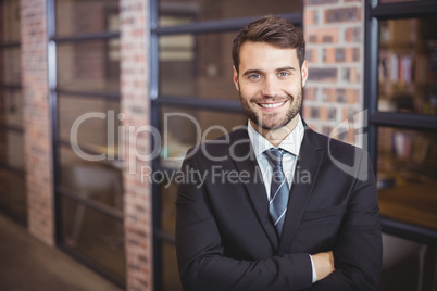 Handsome businessman with arms crossed standing in office