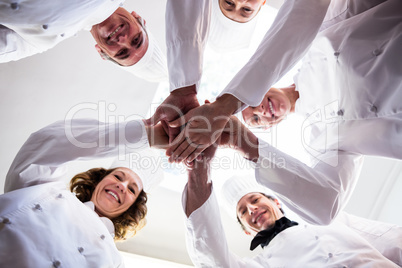 Portrait of chefs team putting hands together and cheering