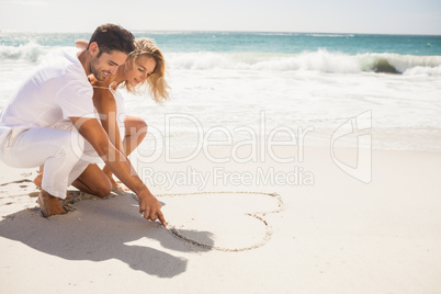 Couple drawing heart on sand