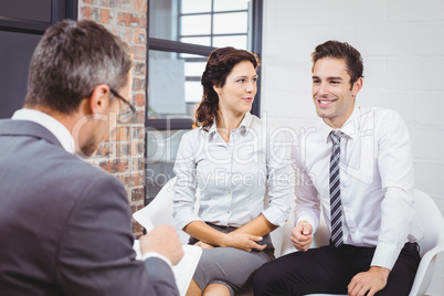 Business professional discussing with smiling clients