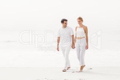 Happy young couple walking on the beach