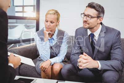Business professionals discussing while sitting on sofa