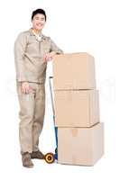 Delivery man standing beside luggage trolley with cardboard boxe