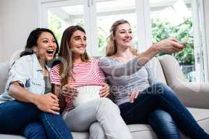 Female friends with remote and popcorn watching movie