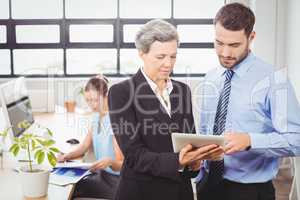 Businesswoman explaining male colleague over digital tablet