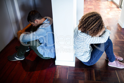 Couple sitting on opposite sides of the wall