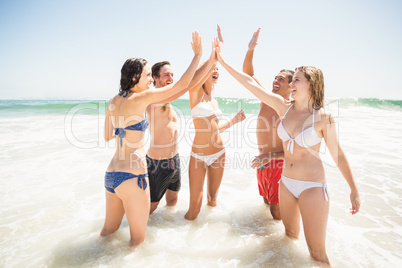 Happy friends giving a high five on the beach