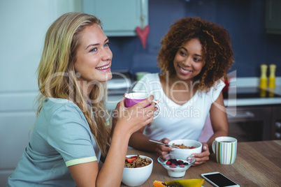 Female friends having breakfast at table in kitchen