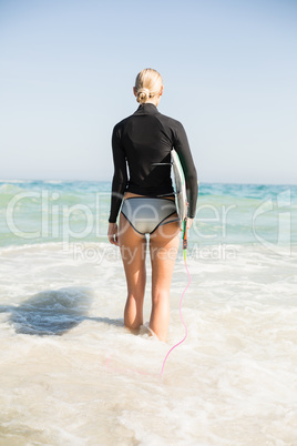 Rear view of woman with surfboard standing on the beach