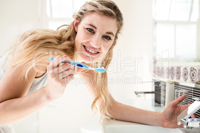 Portrait of happy woman brushing teeth at sink