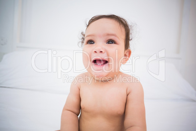 Cute smiling baby girl sitting on bed