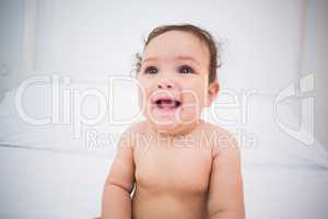 Cute smiling baby girl sitting on bed