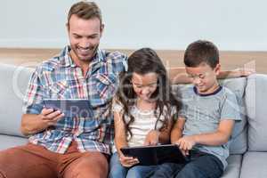 Father and siblings using digital tablet