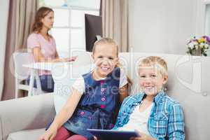 Children with digital tablet while mother in background