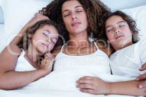 Children sleeping together with their mother