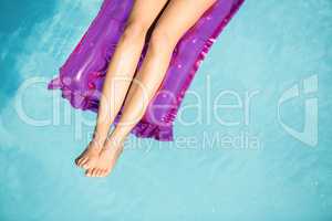 Woman in white bikini lying on air bed in pool