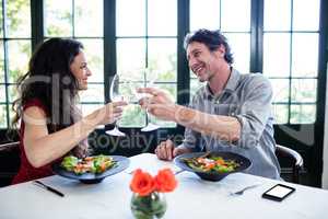 Couple toasting wine glasses at dining table