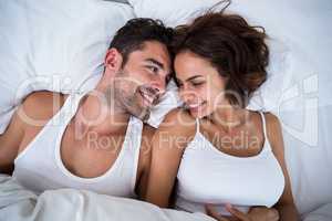 High angle view of smiling couple relaxing on bed