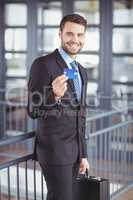 Businessman showing credit card while standing in office