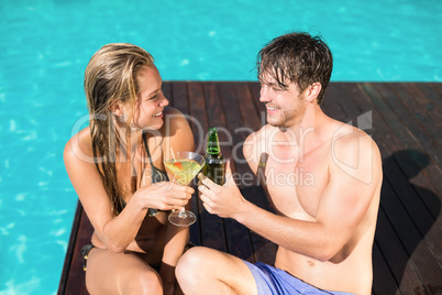 Young couple sitting at the swimming pool