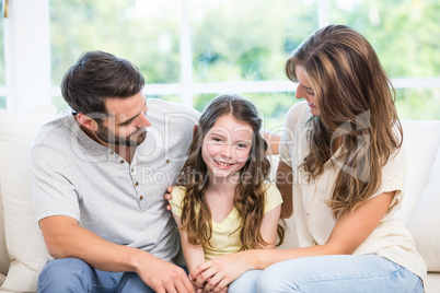 Parents looking at daughter while sitting on sofa