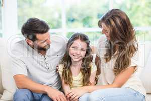 Parents looking at daughter while sitting on sofa