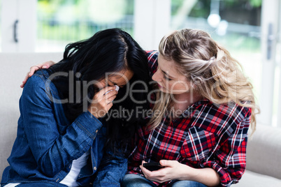 Young woman consoling crying female friend at home