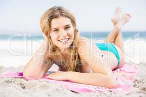 Portrait of happy woman in bikini lying on the beach