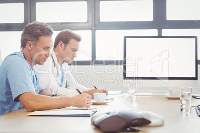 Doctors writing a report in conference room