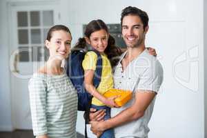 Portrait of happy family with daughter holding lunch box