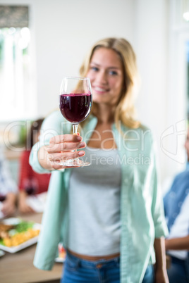 Smiling woman offering red wine glass