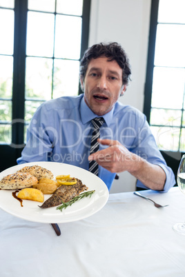 Frustrated man holding a plate of meal in restaurant