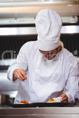 Chef sprinkling spices on dish