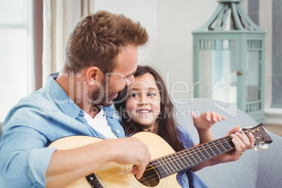 Young man playing guitar with daughter